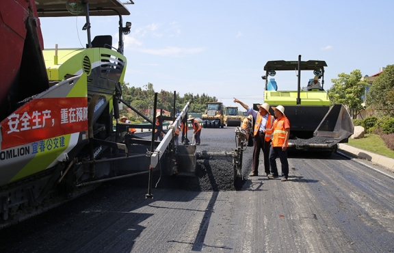 攤鋪機(jī)、壓路機(jī)等設(shè)備緊張有序運(yùn)行，高達(dá)170℃的瀝青混合料炙烤著公路人